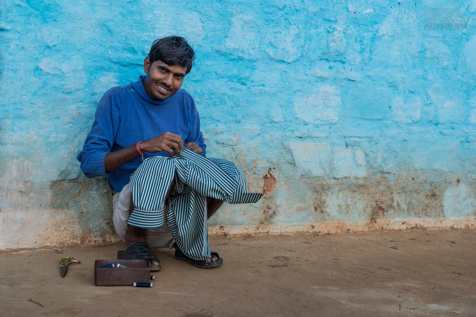 Orchha - Man In the early morning a young man is busy with needle and thread to repair a shirt . Stefan Cruysberghs
